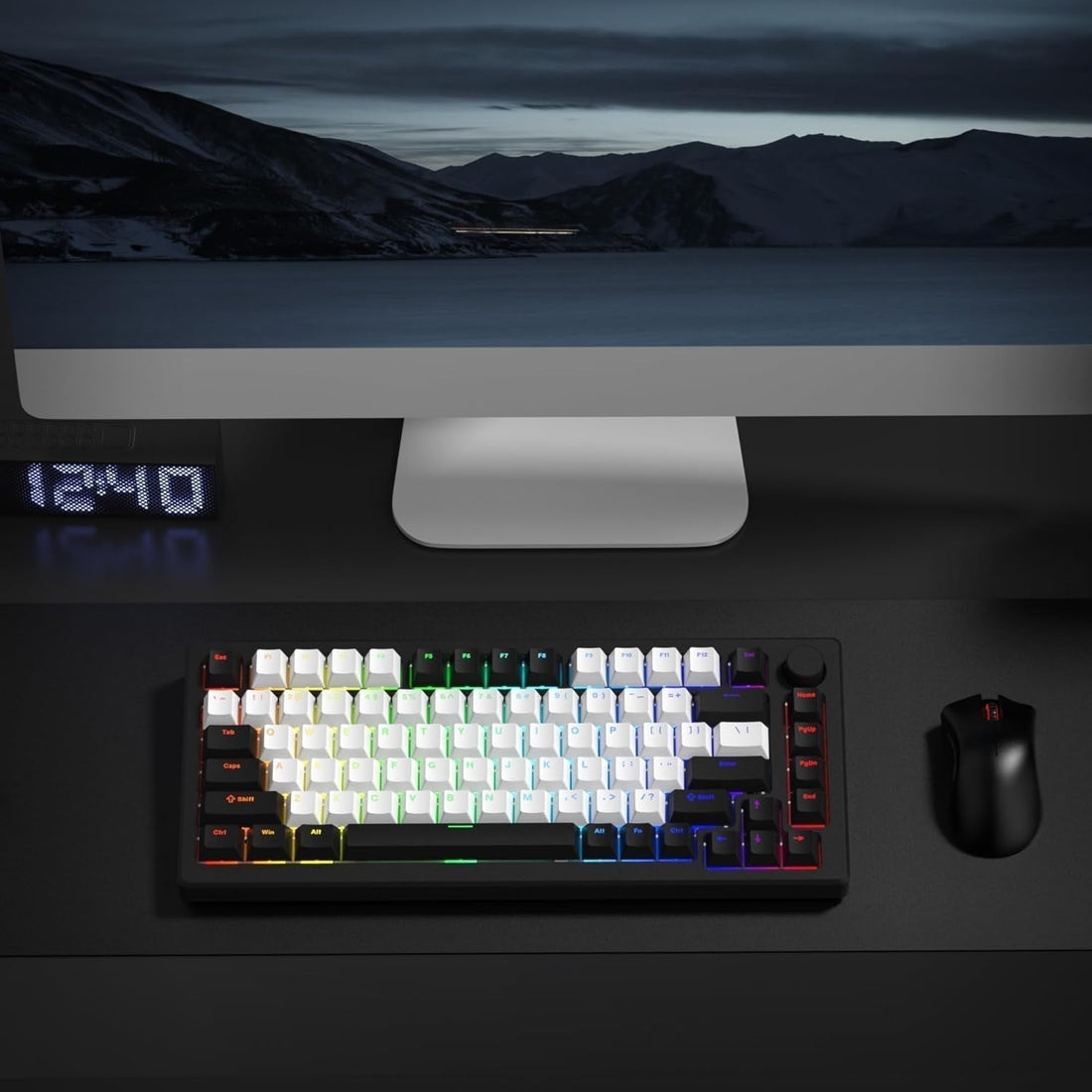 Black and white keyboard with RGB on desk next to mouse and monitor