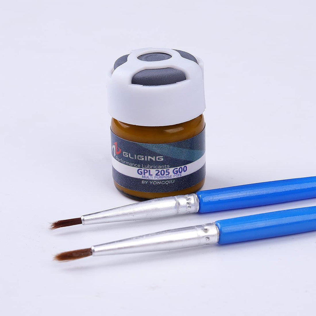 Krytox 205g0 keyboard switch lube next to two small paint brushes on white background