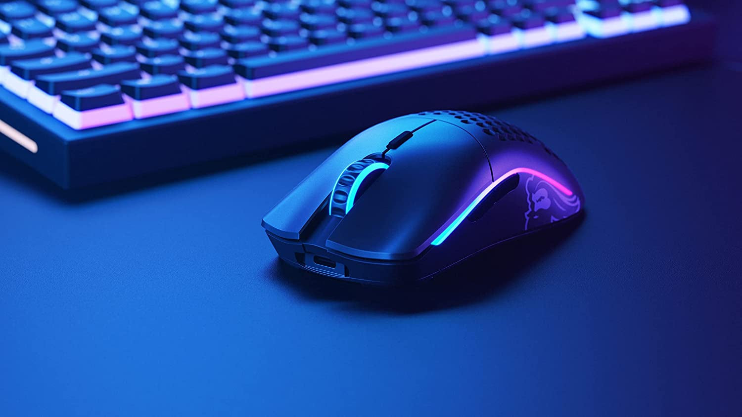 Glorious Model O wireless gaming mouse on a desk setup with RGB keyboard