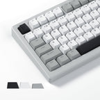 Creamy white and gray Cherry profile PBT keycaps installed on a mechanical keyboard, with black, white, and gray colorway swatches shown below