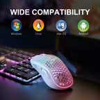 White honeycomb shell wireless gaming mouse with pink and green RGB lighting resting on a black RGB mechanical keyboard on a dark desk surface, with bold white text reading "WIDE COMPATIBILITY" at the top and four OS icons below labeled Windows, Linux, Mac OS, and Android