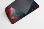 Smooffly galaxy gaming mouse pad partially folded back on a white surface, showing the vibrant cosmic nebula print on the top surface with deep red, teal, and purple hues, and the dark grey textured fabric underside visible where it is curled over