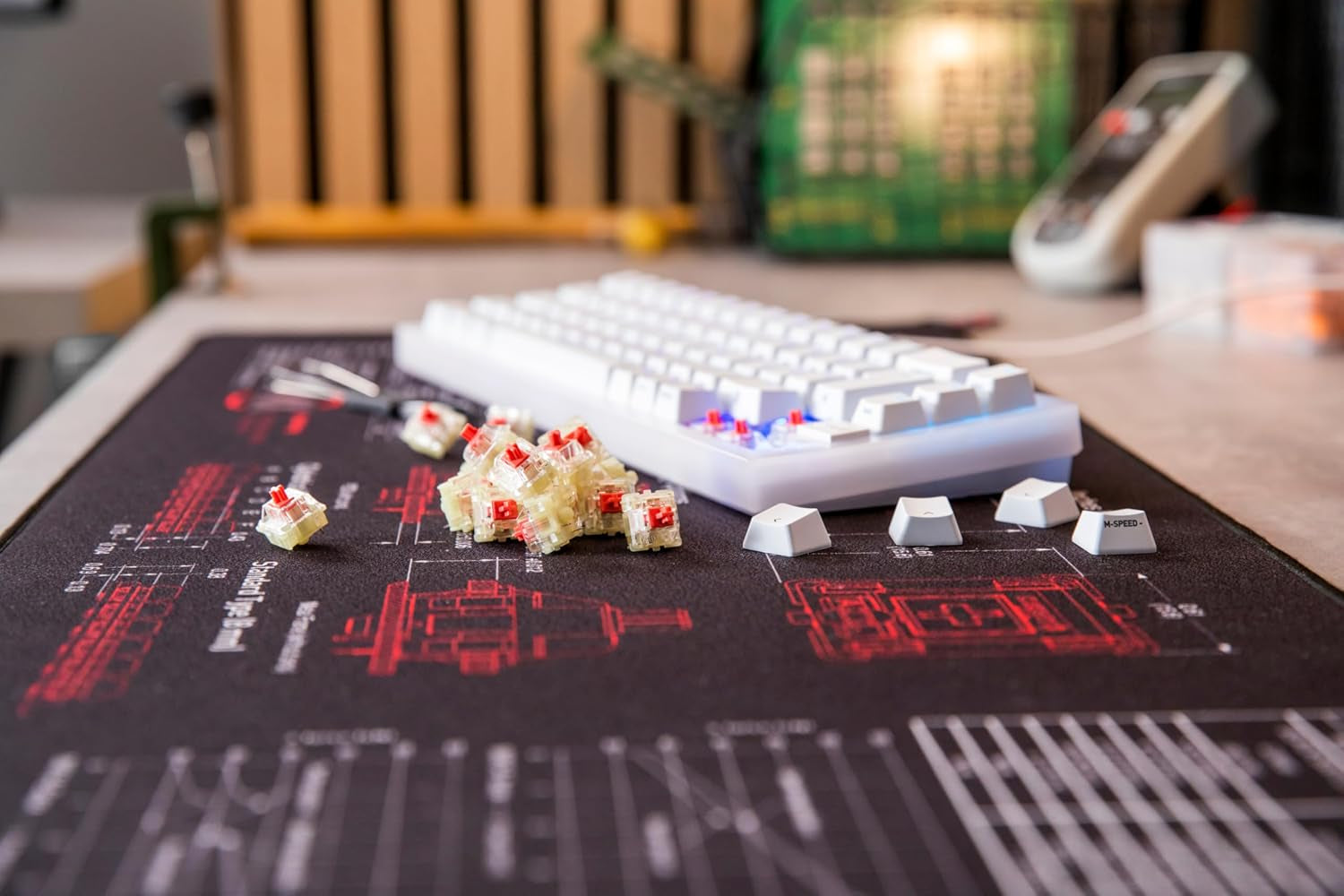 Cherry MX2A Silent Red switches scattered on a dark desk mat next to a white 60% mechanical keyboard with keycaps removed during a switch swap