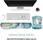 Keyboard and marble-patterned mouse pad and wrist rest set on a white desk with a computer monitor.
