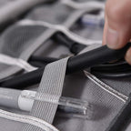 Person putting a black pen in a OrgaWise Grey Portable Three-Layer Electronics Organizer