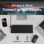 Top-down flat lay of Keychron K2 V3 keyboard on a white desk connected via USB-C cable to an iMac, with a MacBook, iPhone, wireless mouse, and magazine nearby, with Bluetooth 5.2 and USB Wired icons and text reading Wireless and Wired Connect up to 3 Devices