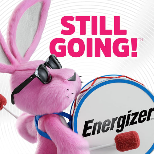 Energizer Bunny mascot in pink fur with black sunglasses playing a white and blue bass drum with Energizer logo, with text reading Still Going! on white background