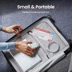 Hands placing a white compact 30W USB-C wall charger into the mesh interior pocket of an open gray hard-shell rolling suitcase on a gray carpet, with a white coiled USB-C cable and boarding pass also visible in the mesh pocket, bold white text reading Small and Portable, Perfect travel companion