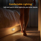 Person walking past motion-sensor night light illuminating a dark bedroom at night