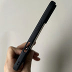 Hand holding BESDYNASTY matte black silicone iPhone case vertically showing left side profile with precise volume button cutout, silent switch cutout, and USB-C port opening at bottom, slim matte black TPU frame against light gray background