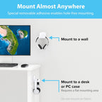 Mount Almost Anywhere infographic showing two installation locations: white over-ear headphones hanging on a TotalMount hanger mounted to a white wall beside a monitor with blue arrow callout reading Mount to a wall, and the same headphones hanging on a TotalMount hanger mounted to the side edge of a white standing desk with blue arrow callout reading Mount to a desk or PC case, Requires a flat mounting area, Do not mount on fabric