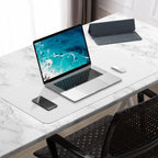 Home office desk setup with laptop, mouse, and phone on top of a white 30x14 desk mat