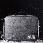 OrgaWise Grey Portable Three-Layer Electronics Organizer on white sidewalk with rain pouring down, showcasing waterproof design